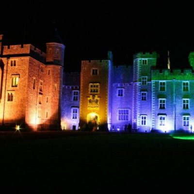 Dunster Castle floodlit in colourful light for Dunster by Candlelight