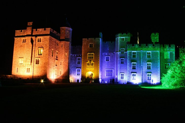 Dunster Castle floodlit in colourful light for Dunster by Candlelight