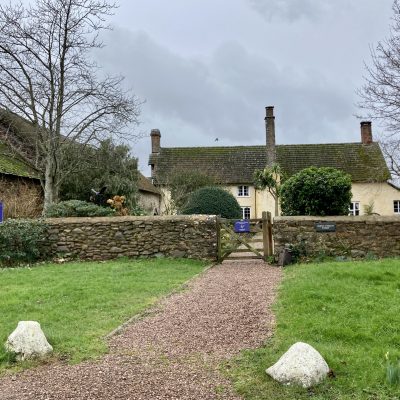 Exmoor Owl & Wildlife Sanctuary Allerford yellow house with stone walls and wooden gate and gravel driveway