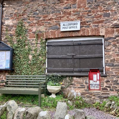 Allerford Post Office with shutters closed bench in foreground