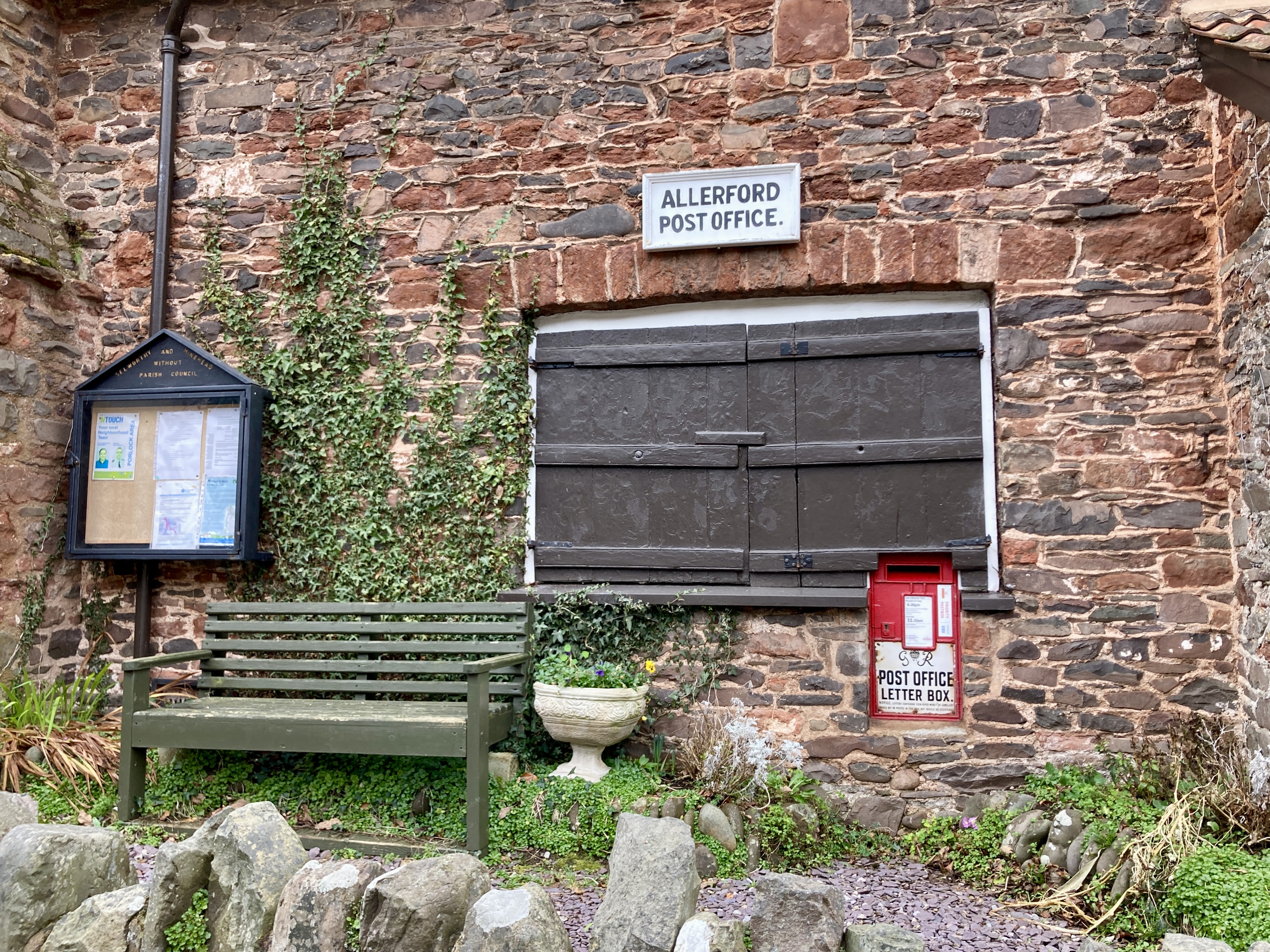 Allerford Post Office with shutters closed bench in foreground