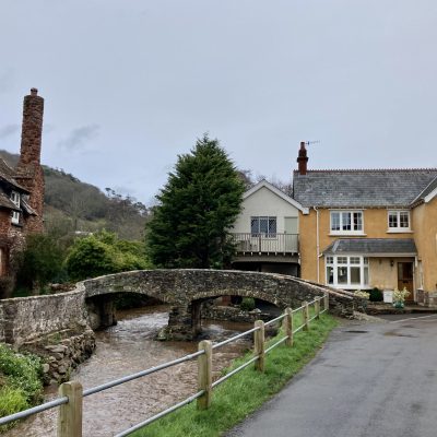 Allerford village with yellow house and cobblestone bridge