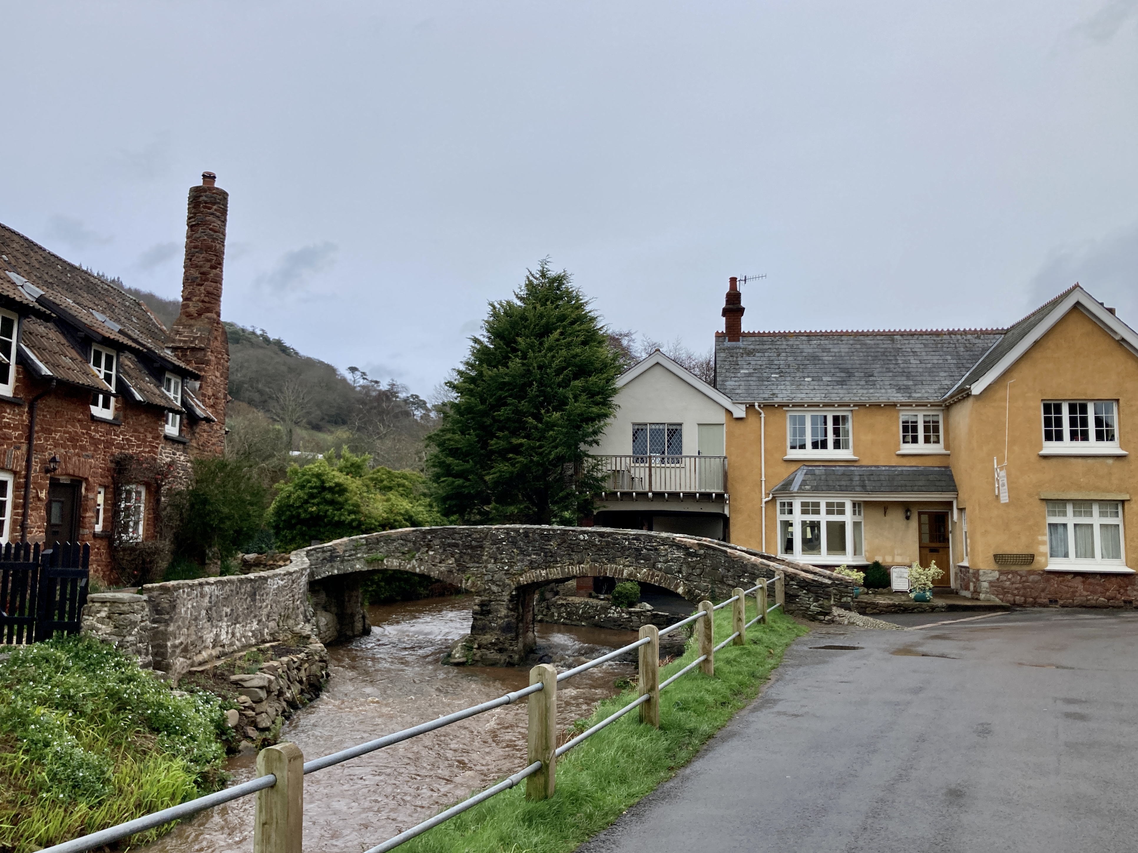 Allerford village with yellow house and cobblestone bridge