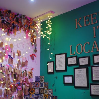 Corner of Charlie Fridays cafe restaurant with pictures and flowers and fairy lights and "Keep it local" sign