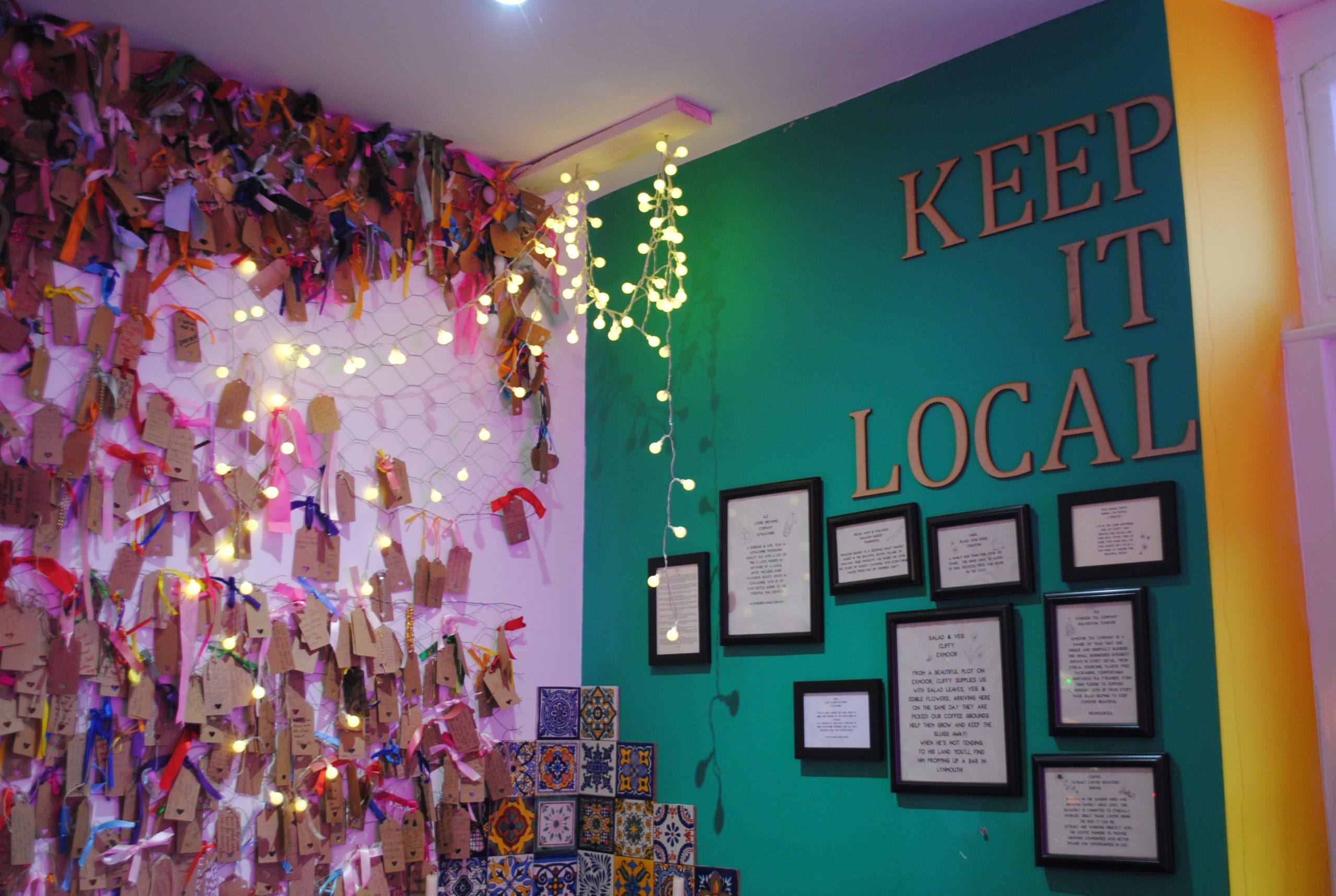Corner of Charlie Fridays cafe restaurant with pictures and flowers and fairy lights and "Keep it local" sign