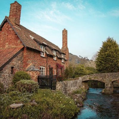 Cobblestone Medieval Historic Backhorse Bridge and house behind it with river looking blue