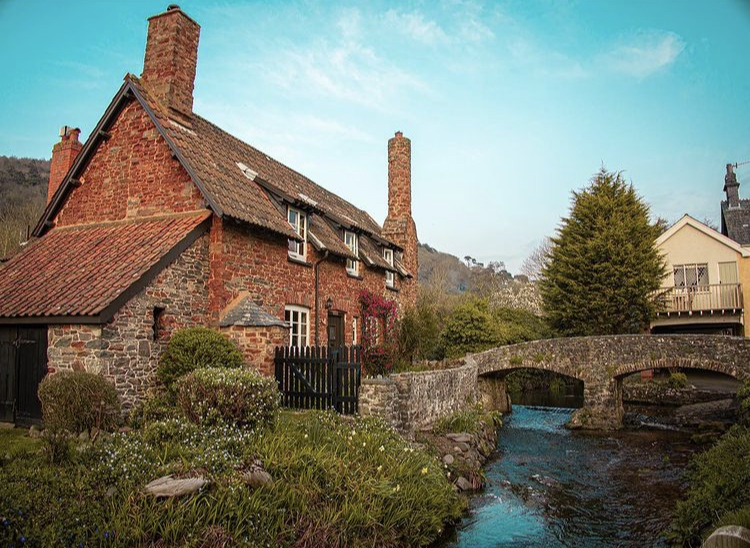 Cobblestone Medieval Historic Backhorse Bridge and house behind it with river looking blue