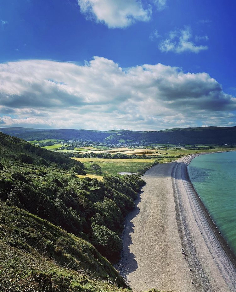 View of Bossington beach from above with sunshine and clouds and sea and land either side