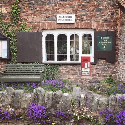 Allerford Post Office and Tea Rooms with pretty purple flowers and shutters open