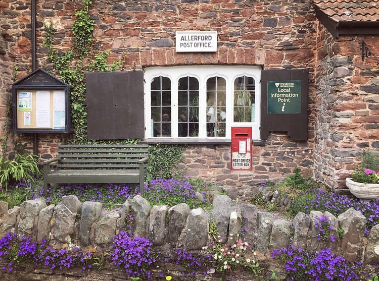 Allerford Post Office and Tea Rooms with pretty purple flowers and shutters open