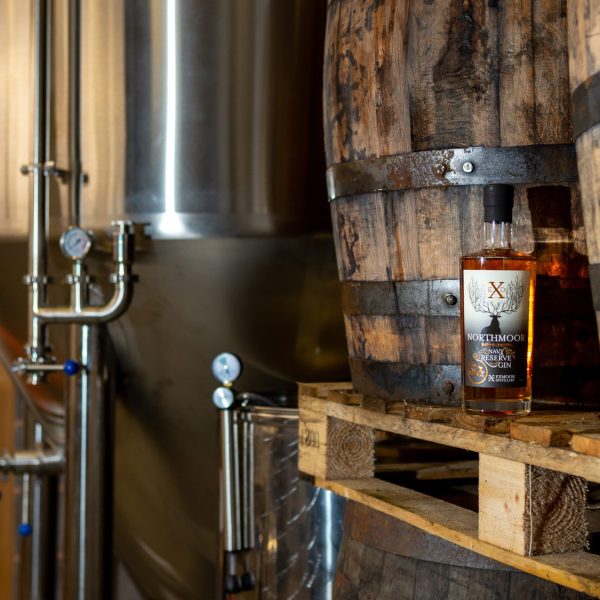 Exmoor distillery barrels and equipment with a bottle of Blackmoor Rum perched on a wooden shelf to one side