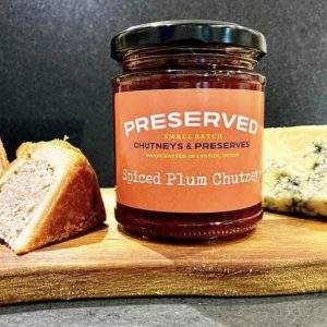 Preserves available at the Lynton Christmas Market - orange jar of preserve on a chopping board with a slice of pork pie and some cheese