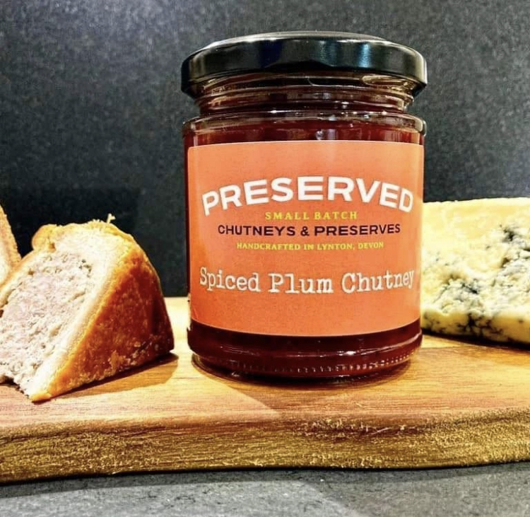 Preserves available at the Lynton Christmas Market - orange jar of preserve on a chopping board with a slice of pork pie and some cheese