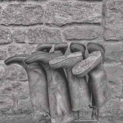 Black and white photo of wellies upside down on a welly rack