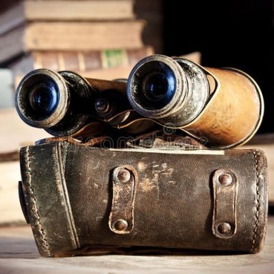 Vintage binoculars on leather case with books