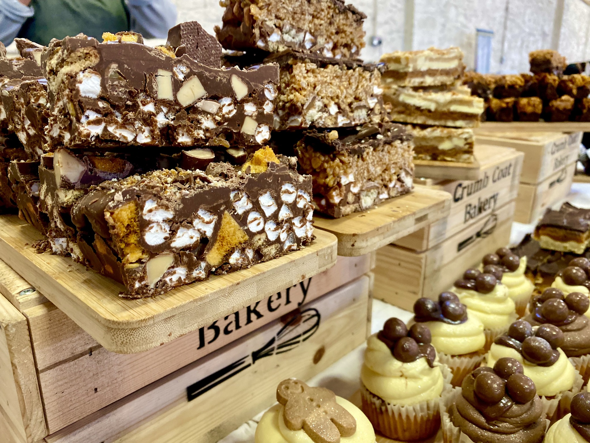 Crumbcoat Bakery Rocky Roads on display on wooden boards and boxes with cupcakes too