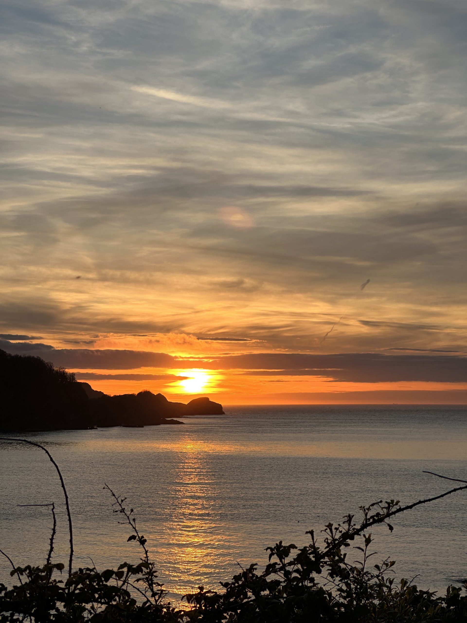 A glowing orange sunset over a silvery blue sea along the Exmoor coast line