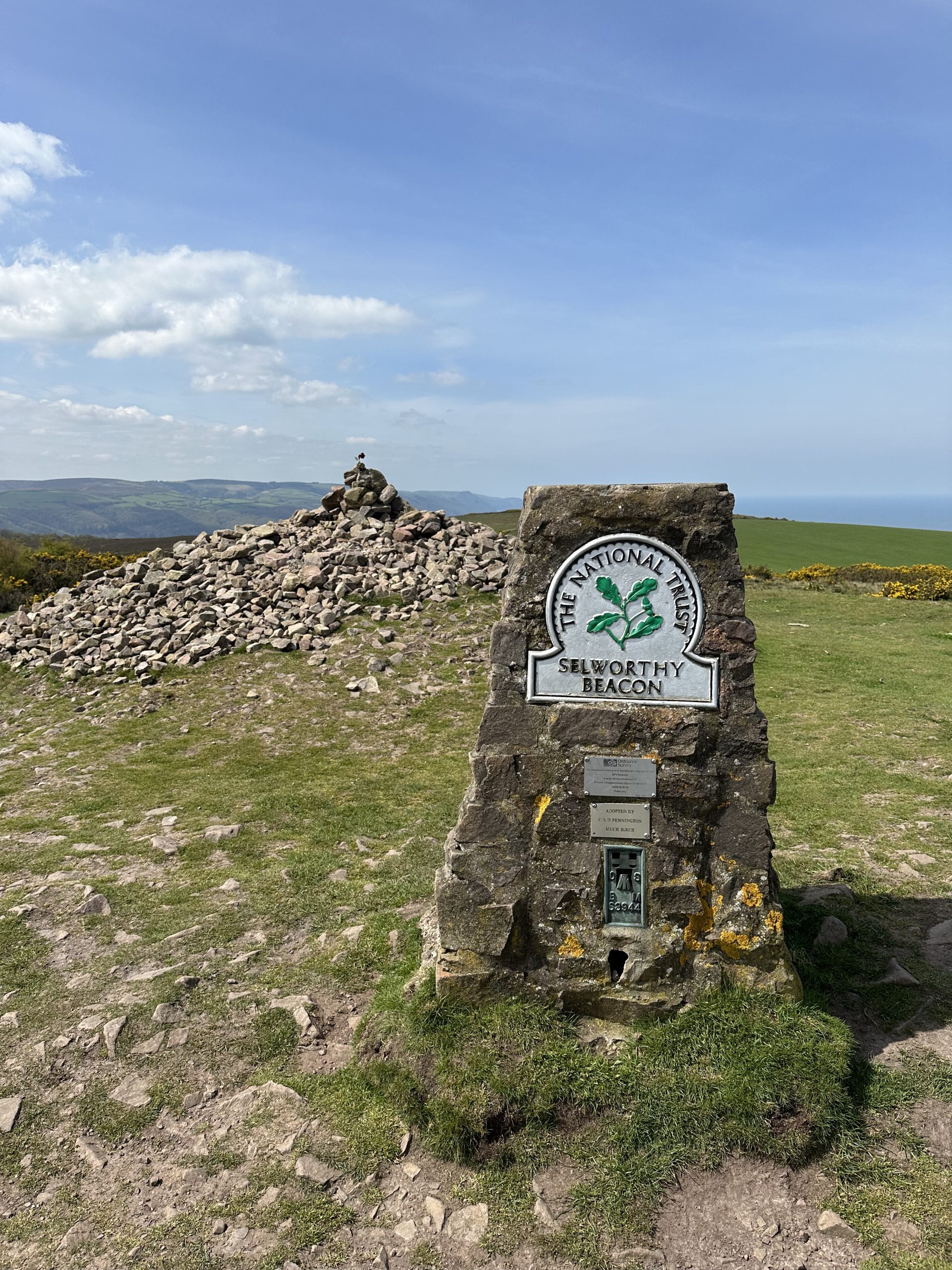 Selworthy Beacon - a rock tower with a National Trust plaque on it, in front of the view of Exmoor