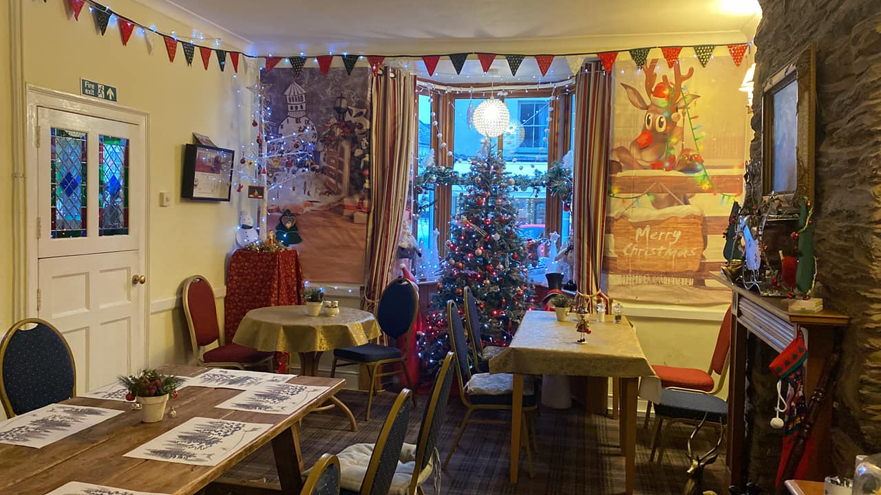 The Copper Kettle Dulverton at Christmas - inside with Christmas tree set up in the window and festive decorations around the tables and chairs of the cafe