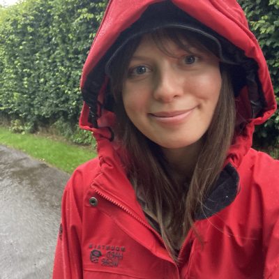 Smiling girl in raincoat with hood up in the rain in the countryside